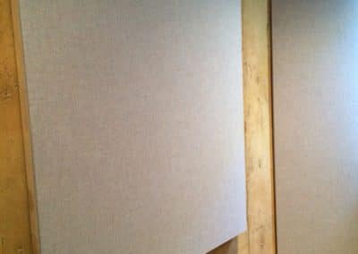Acoustic treatment panels with stretched fabric gray covers and wood frames hung on a wall