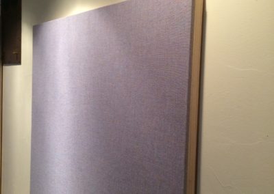 Acoustic treatment panels with stretched fabric gray covers and wood frames hung on a wall