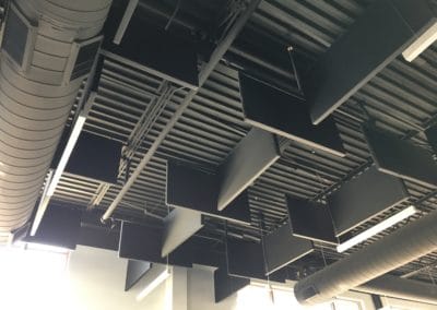 Black ceiling acoustic treatment baffles hung on black industrial ceiling