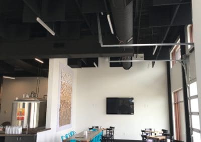 Black ceiling acoustic treatment baffles hung on black industrial ceiling