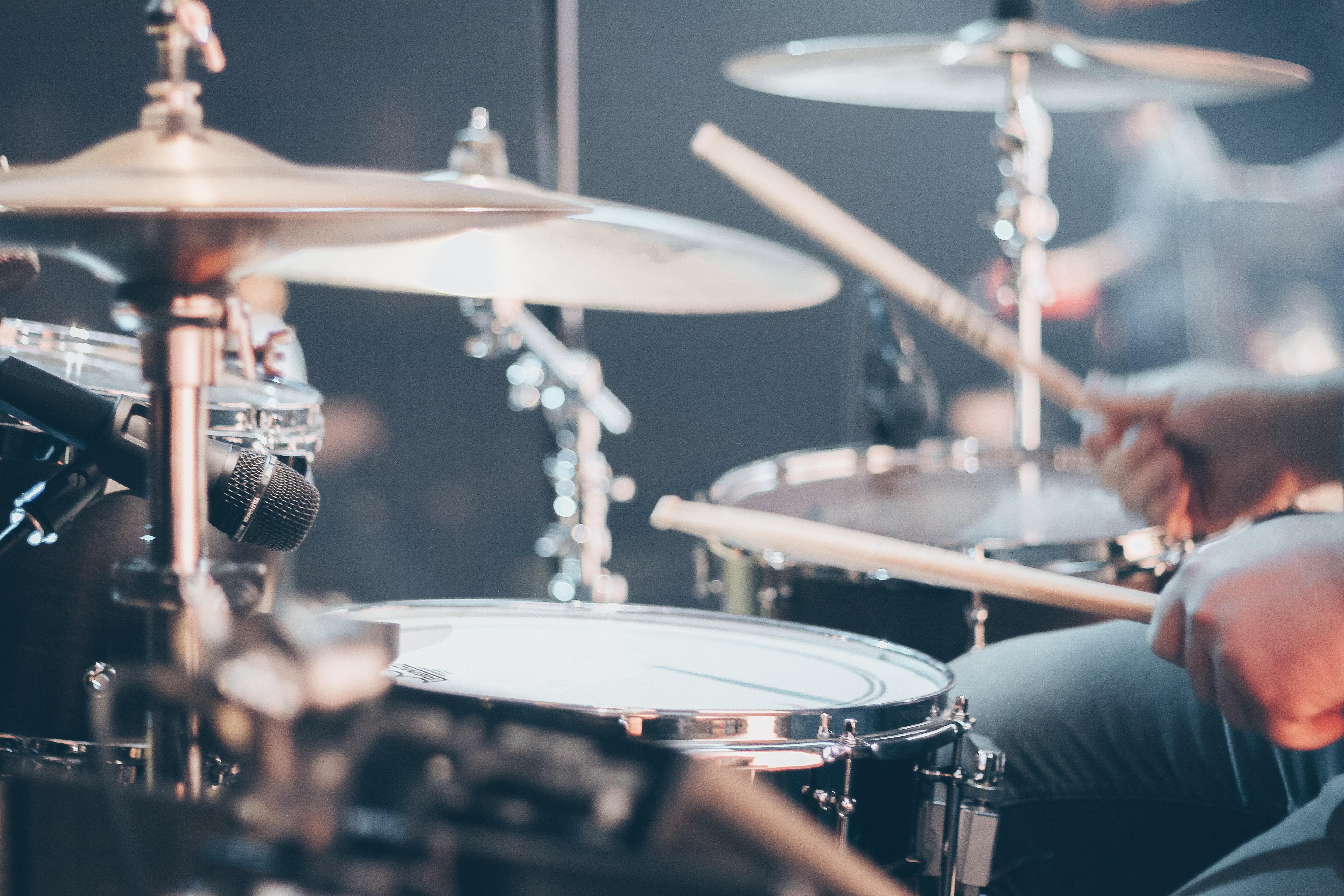 close up of man playing drum set with motion blur on drumsticks