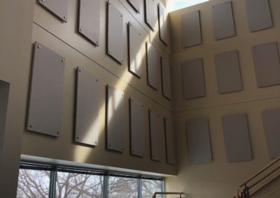 Large interior wall natural light with acoustic treatment panels stand off mounted to wall gray with metal fixtures above stairwell